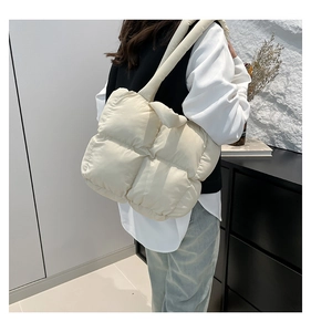 Close-up of cream quilted puffer tote bag with large square stitching on model