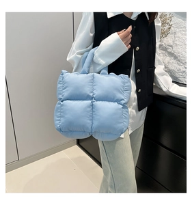 Quilted light blue tote bag shown in use by a model for size and drape reference