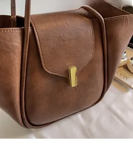 Detailed shot of gold metal lock buckle and stitching on brown vintage tote bag
