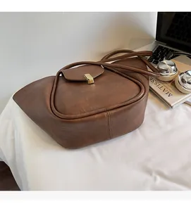 Brown vintage faux leather handbag with gold metal clasp on a desk with office accessories