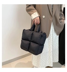 Chic black quilted tote bag shown on model with stylish brown blazer for city commute