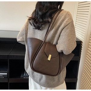 Detail view of the dark brown textured leather tote bag with a gold metal lock closure