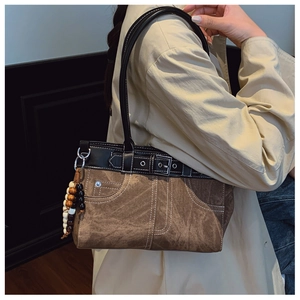 Detail of vintage brown shoulder bag featuring contrast stitching and beaded tassels