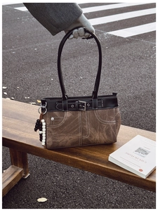 Detail of retro canvas shoulder bag with leather trim and decorative belt buckle detail