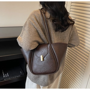 Close-up of vintage brown tote bag featuring golden buckle and leather texture