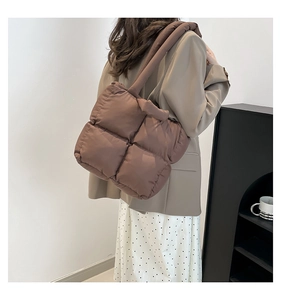 Detailed view of dark brown quilted tote bag on shoulder with plush puffer style texture