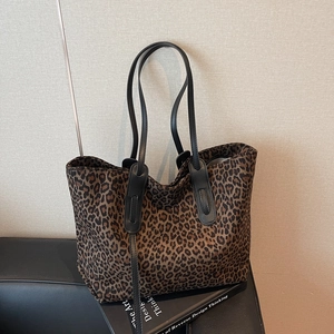 Vintage leopard print tote bag with black leather straps on a stylish studio background