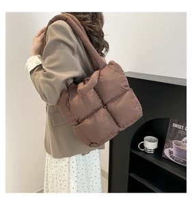 Detailed side view of a brown quilted puffer tote bag with a soft padded texture