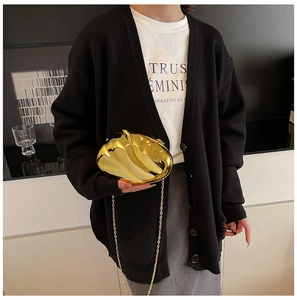 Artistic gold wave clutch with metallic chain strap worn by a model in minimalist setting
