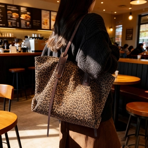 Vintage leopard print tote bag with leather handles in a warm cafe scene