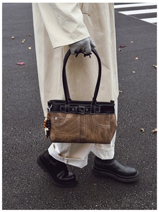 Detail view of a vintage canvas shoulder bag with leather buckle and tassel decoration