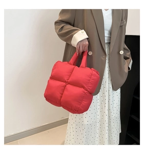 Detail of red quilted puffer tote bag made of waterproof nylon on model shoulder