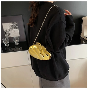 Chic heart-shaped champagne gold metallic bag with slim chain on black outfit
