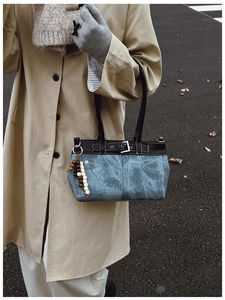 Close-up of retro denim shoulder bag with leather trim and decorative beaded charm