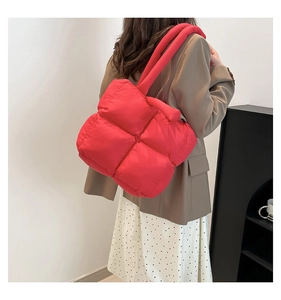 Detail of red quilted tote bag with puffy cloud texture shown on model shoulder