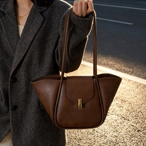 Close-up of dark brown leather tote bag with gold lock and sleek shoulder straps