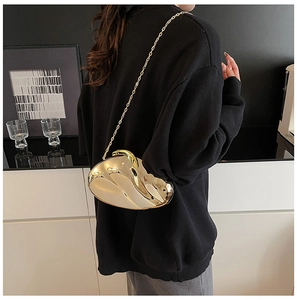 Chic gold metallic clutch bag with slim chain strap shown on model in modern setting