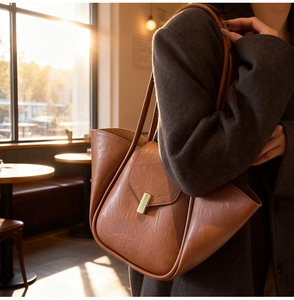 Close-up of brown textured leather tote bag featuring a golden buckle in a cozy cafe