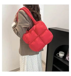 Chic red quilted puffer tote bag shown on shoulder in a minimalist indoor setting