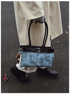 Detail of vintage blue denim handbag with black leather straps and wooden bead charm accessory