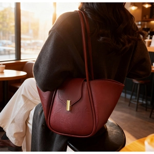 Close-up of vintage burgundy leather tote bag with elegant gold clasp and winged side detail