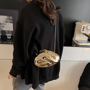 Close-up of golden irregular pebble-shaped acrylic clutch with metallic chain strap