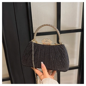 Detail of black evening clutch bag with sequins, crown clasp, and golden ring handle