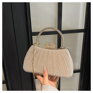 Detailed shot of champagne gold evening bag with crown clasp and rhinestone handle