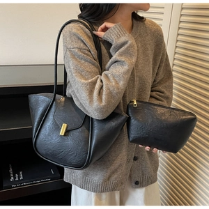 Detail of black pleated faux leather tote bag and small pouch with gold metal lock