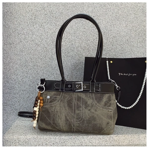 Detail of retro denim shoulder bag with contrast stitching and beaded charm accessory