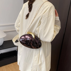 Deep purple metallic acrylic pod-shaped bag shown on a model wearing an ivory coat