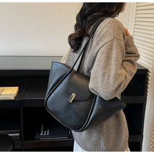 Close-up of black retro tote bag with textured leather and gold metallic buckle clasp