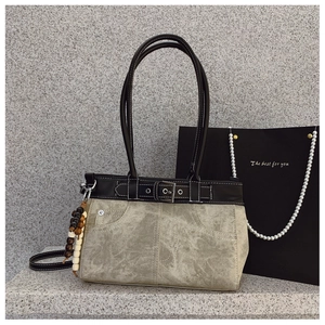 Detail of grey canvas shoulder bag with black leather belt strap and silver buckle accent