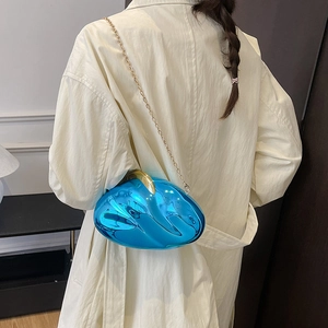 Detail of the bright blue mirrored shell-shaped acrylic clutch bag with a gold chain strap