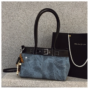 Detail of blue denim tote bag with black leather trim and silver metal buckle