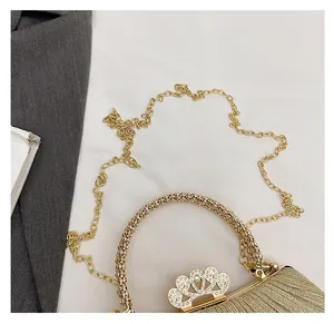 Detail of evening bag with pleated gold glitter fabric and rhinestone crown clasp