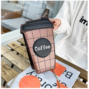 Dettaglio borsa a tracolla a forma di tazza di caffè con catena d'oro su legno