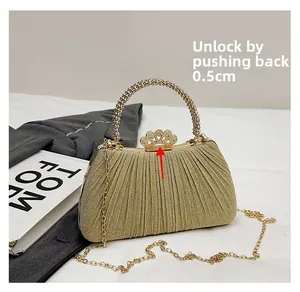 Detail of gold evening bag with sparkling crown clasp and beaded handle on silk fabric