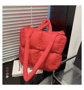 Detail of red quilted puffer tote bag with thick handles and matching shoulder strap