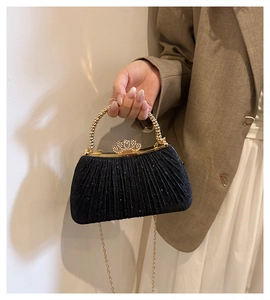 Detail of black sequined evening bag with golden metal handle and rhinestone crown clasp
