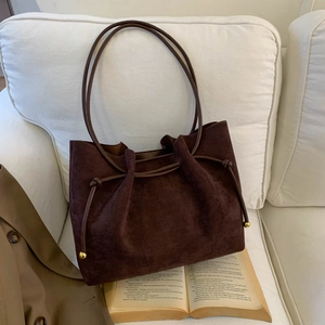 Retro deep brown suede tote bag with drawstring detail on a white sofa with a book