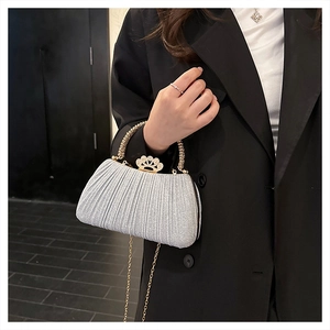 Detail of silver sequin evening bag with crown clasp and golden chain handle