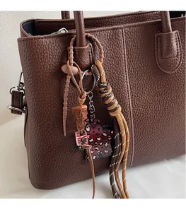 Detail of bohemian bag charm with leopard print and beads on brown lychee leather