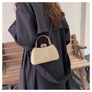Detailed view of golden evening bag featuring pleated glitter texture and crown clasp
