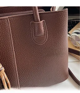 Detail of dark brown pebble leather tote bag with braided tassel and textured finish