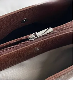 Detail of silver hardware zipper, magnetic buckle and brown lychee grain leather on tote
