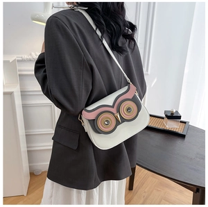 Gros plan d'un sac bandoulière hibou blanc avec des détails de patchwork en cuir rose et gris