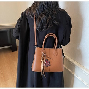 Detailed back view of a brown pebbled leather tote bag with a cute leopard bear charm