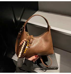 Détail du sac hobo marron vintage avec pompon perlé et texture de cuir mat raffiné