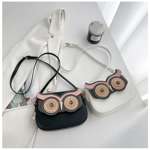 Détail de sacs bandoulière en forme de hibou en cuir noir et blanc avec des yeux en cristal